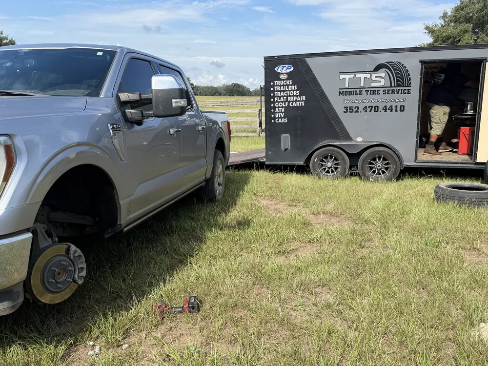 Mobile tire replacement on a pickup truck in a Marion County field, Taylor Mobile Tire Service trailer on site
